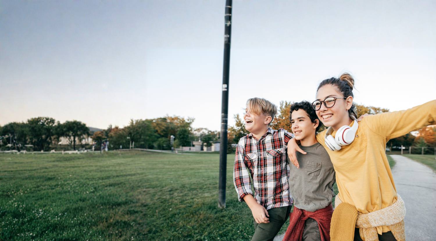 Three students walking together through a park in the late afternoon