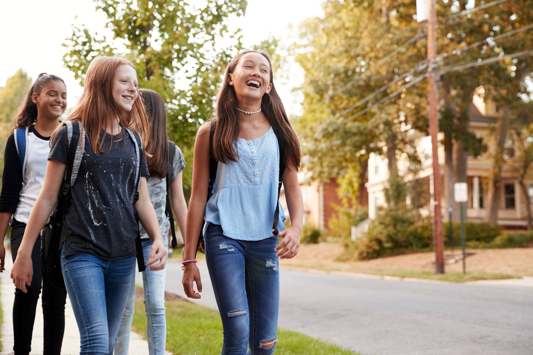 Students walking together along a tree-lined street after school